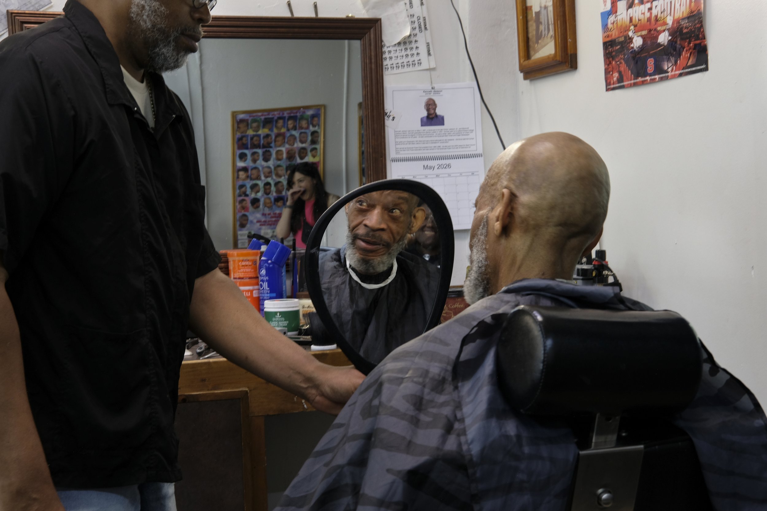  Derrick Franklin holds up a handheld mirror so a patron can check out his fresh cut at Blue Brothers Barber Shop on South Salina Street in Syracuse, May 16, 2026. Photo by Manila Southammavong. 