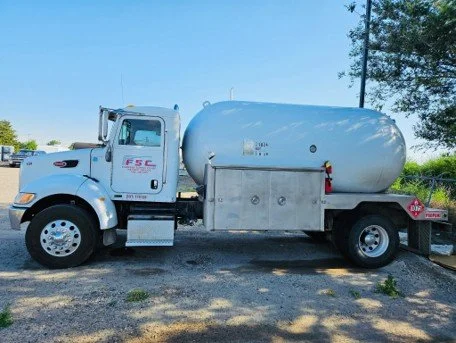White tanker truck parked outdoors on a sunny day
