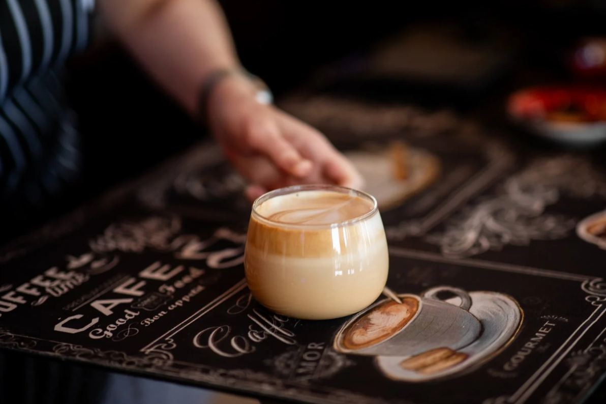 A glass of layered coffee drink on a coffee-themed placemat.