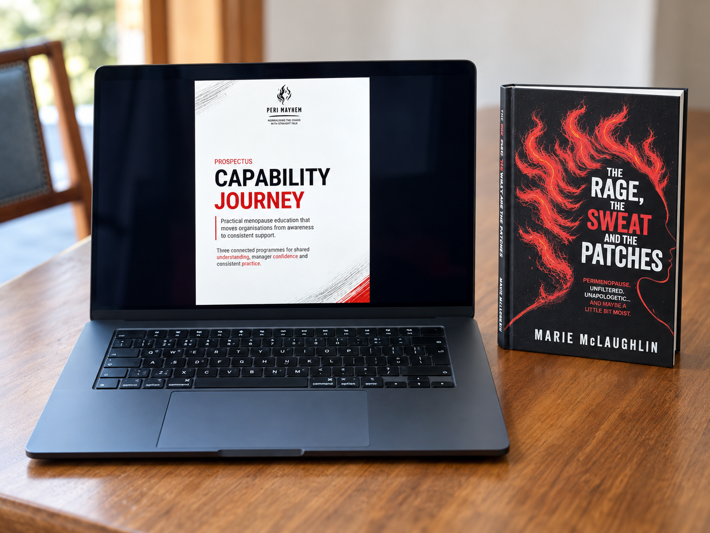 Open laptop displaying a document titled "Capability Journey" on the screen, placed on a wooden table next to a book titled "The Rage, The Sweat, and the Patches" by Marie McLaughlin.