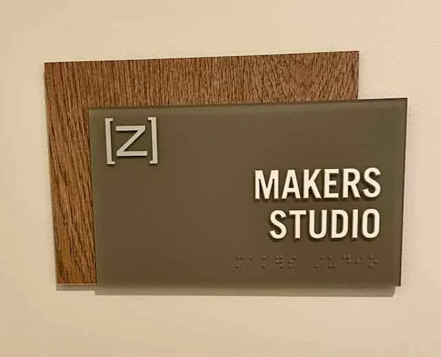 Makers Studio sign mounted on a wall with a wooden backing.