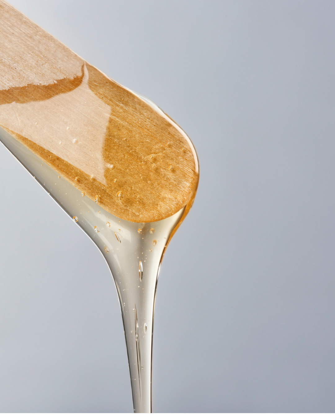 Close-up of honey being drizzled from a wooden spatula.
