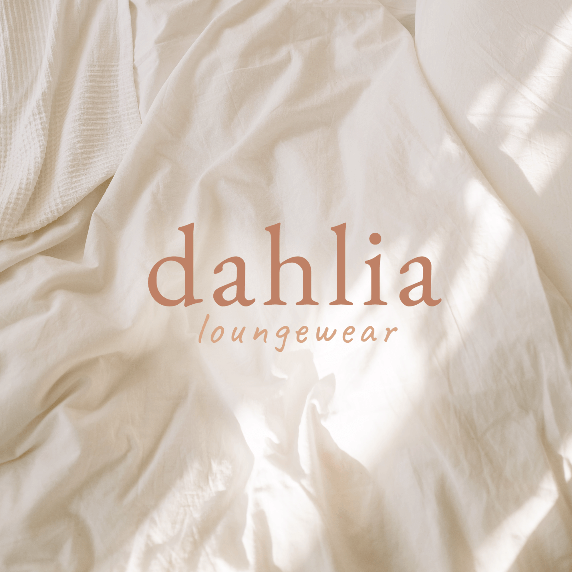 Close-up of a white fabric with part of text reading 'dahlia loungewear' in light brown letters.