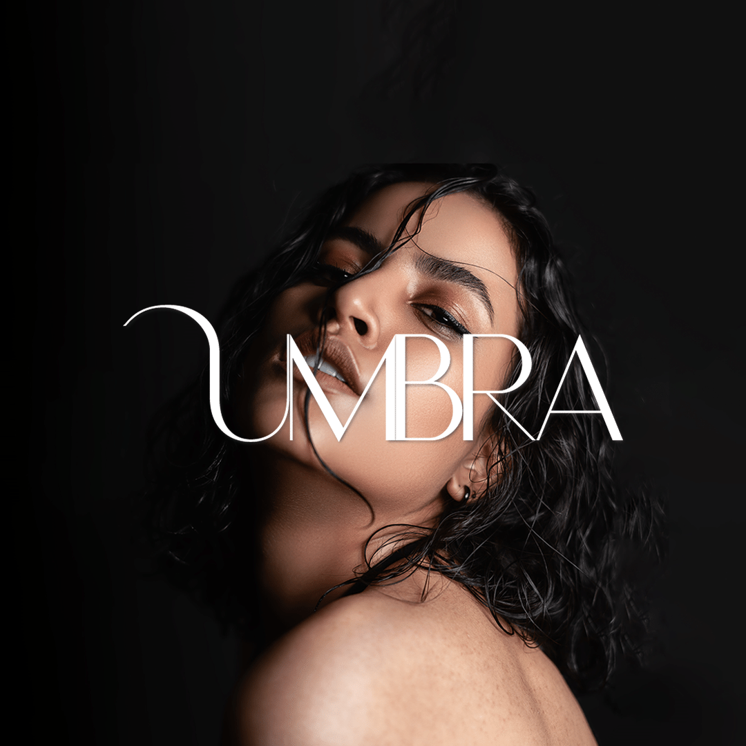 Close-up portrait of a woman with dark, curly hair and makeup, with the word 'UMBRA' overlaid.