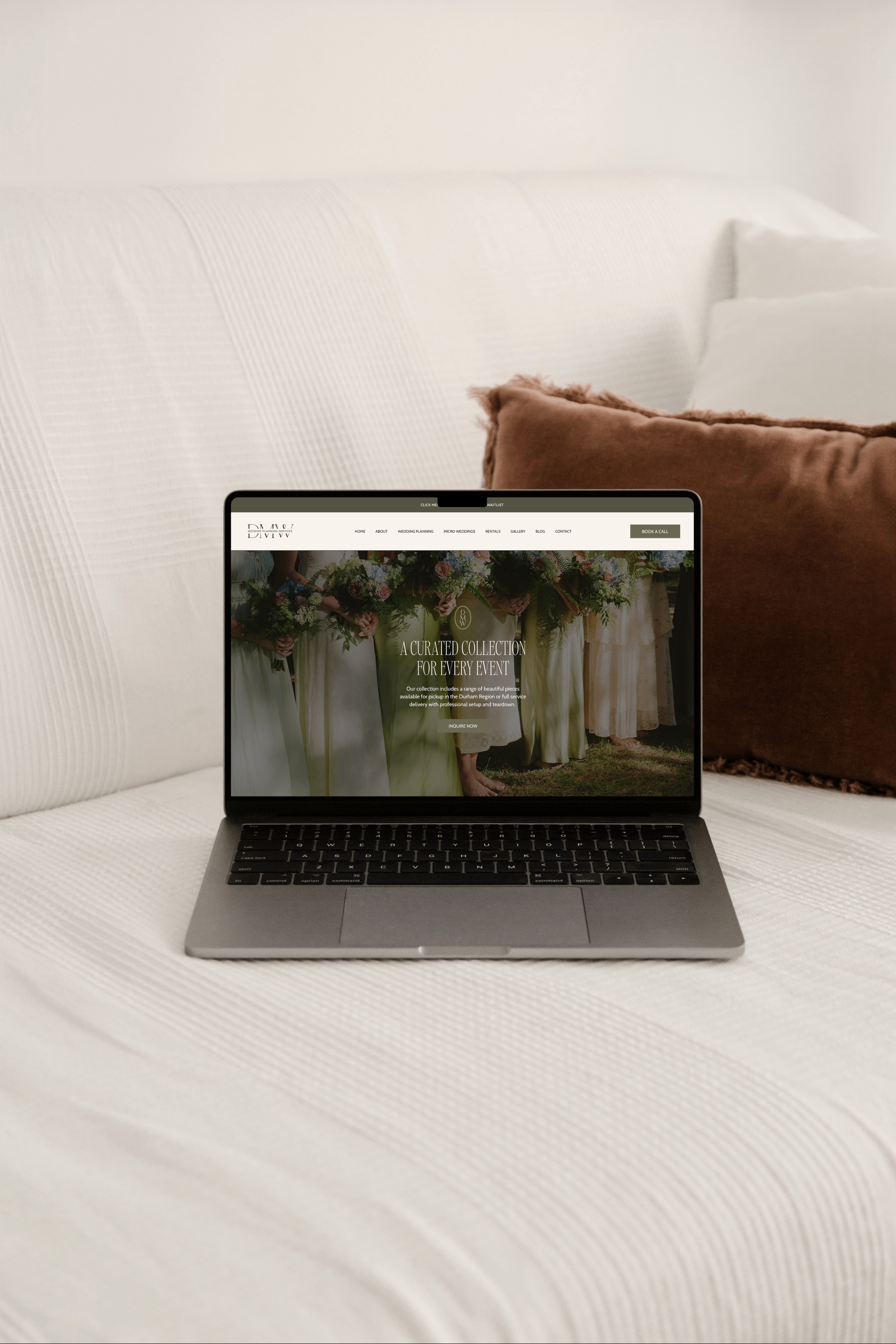 A laptop on a white textured surface with a website on the screen and a brown cushion behind it.
