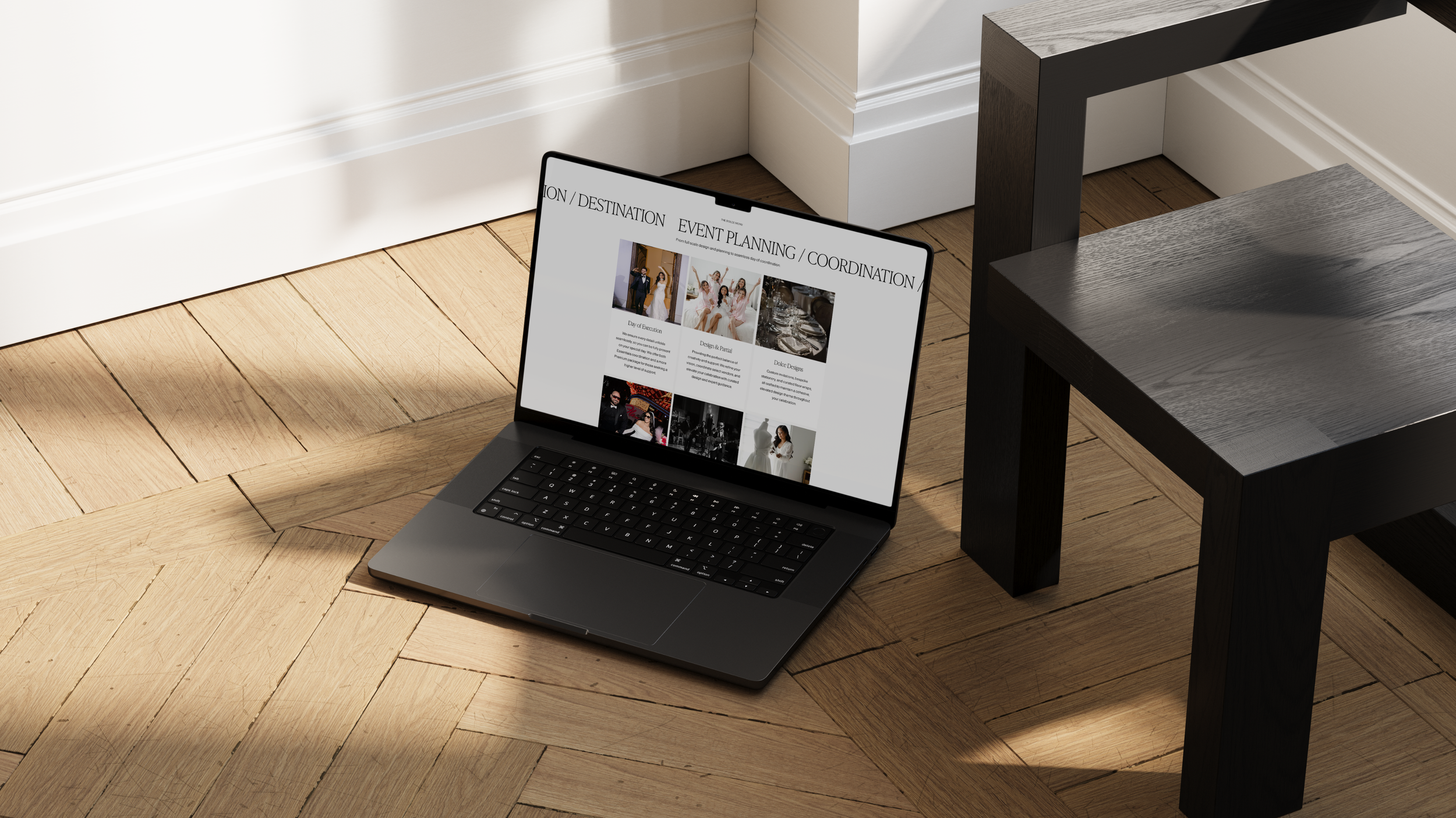 Open laptop on wooden floor displaying event planning website with wedding images and text, next to a black table.