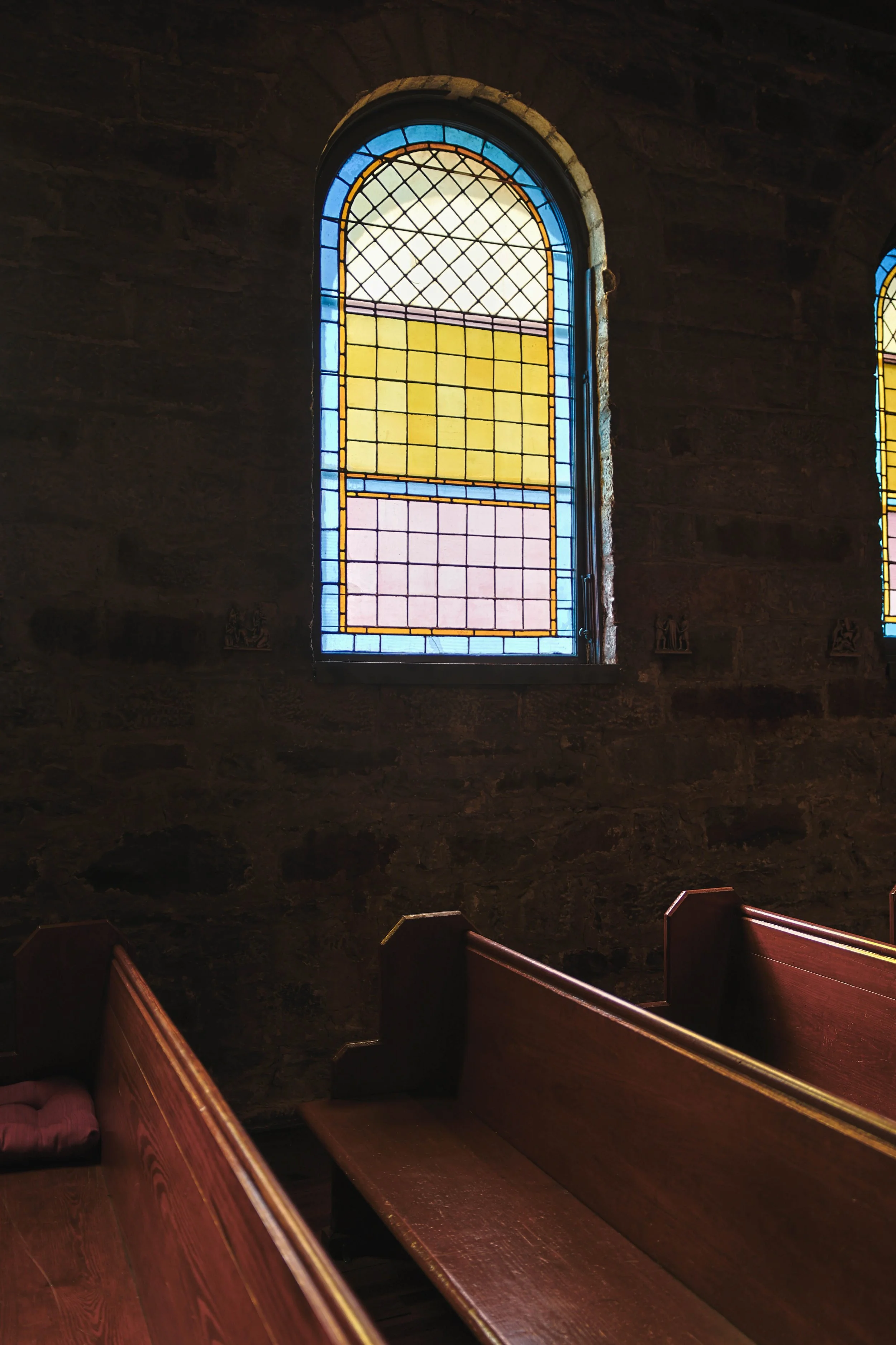Interior of a church with stained glass windows and wooden pews.