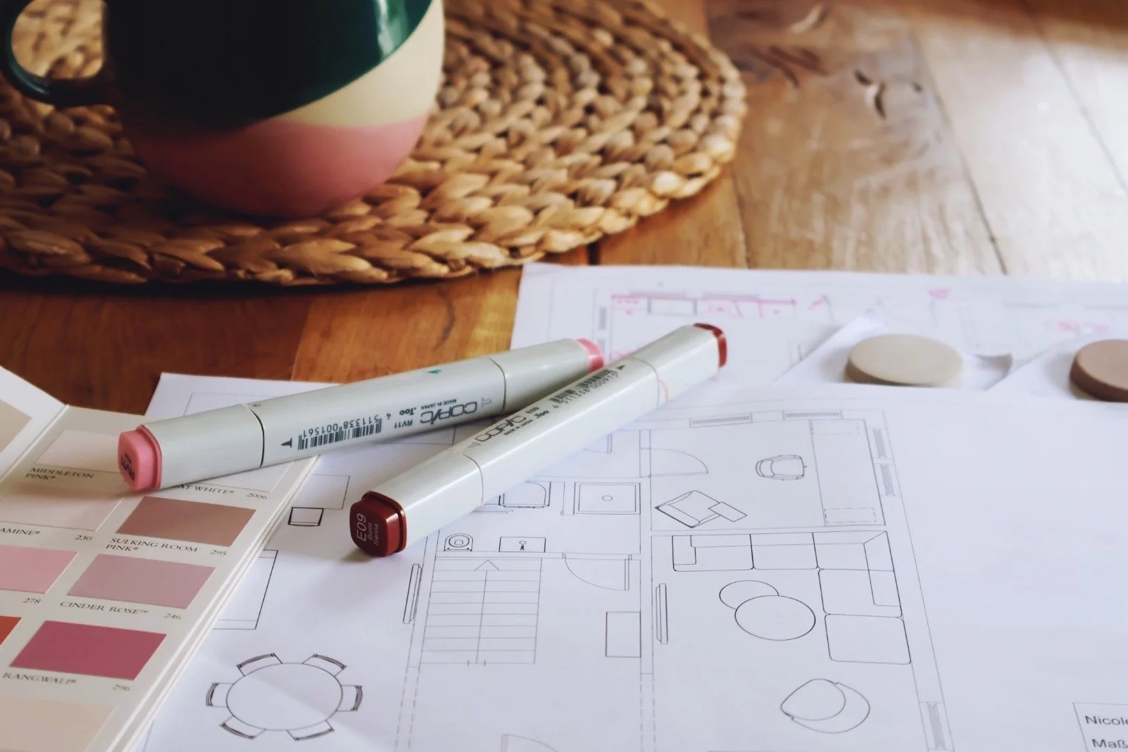 Interior home renovation planning with architectural blueprints, color swatches, and markers on a wooden table.