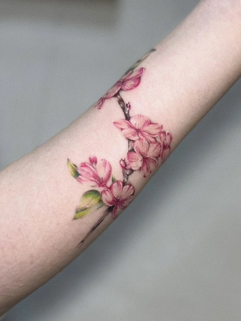 ピンク色の花が描かれた腕のタトゥー