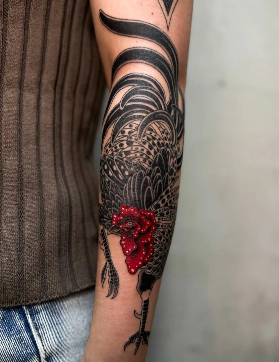 黒と赤の色彩の入り混じったタトゥーの腕のデザイン