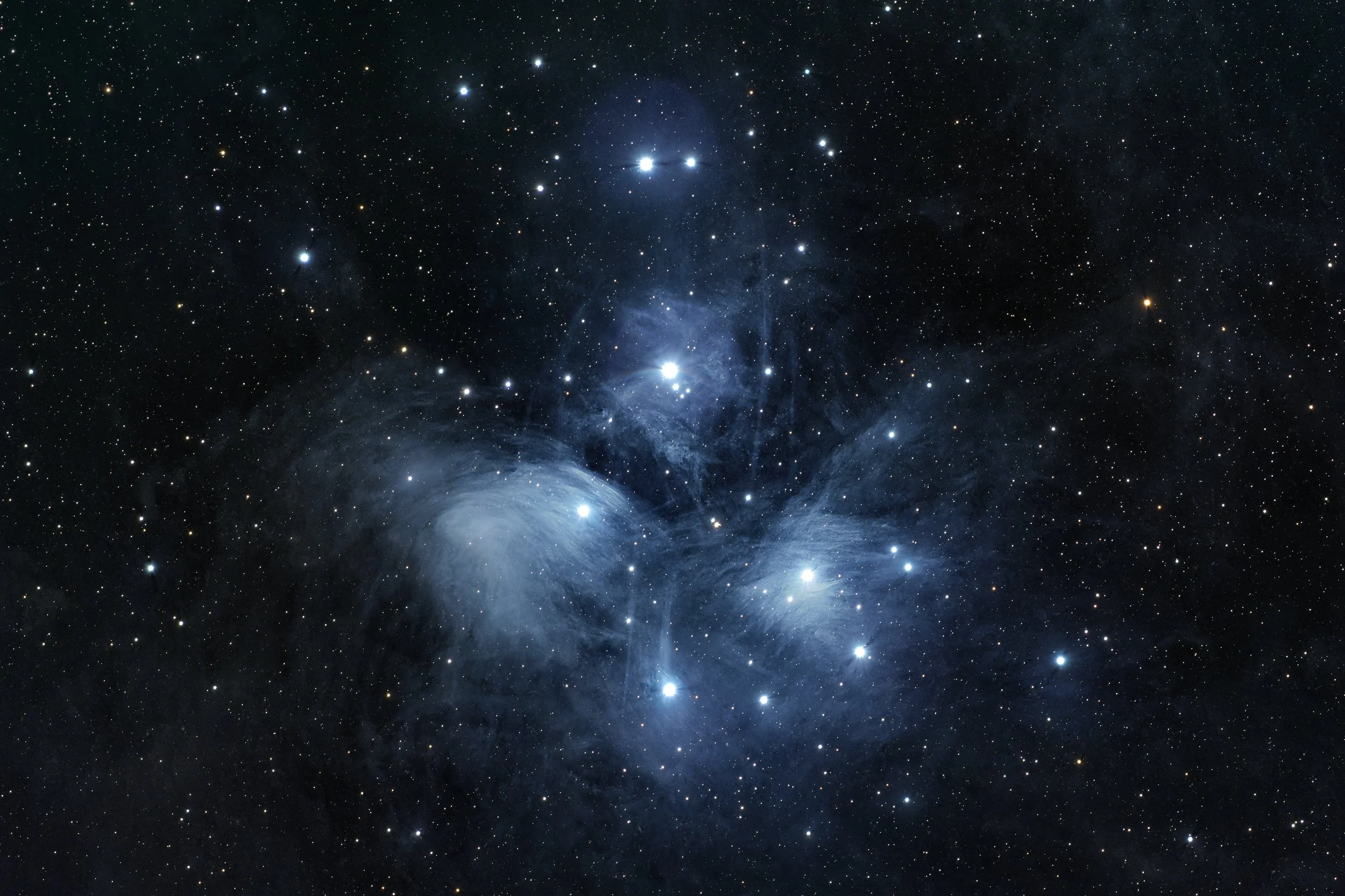 Astrophotography deep space image of Pleiades star cluster with bright stars and surrounding blue reflection nebulae, showing a vast number of stars and cosmic dust.