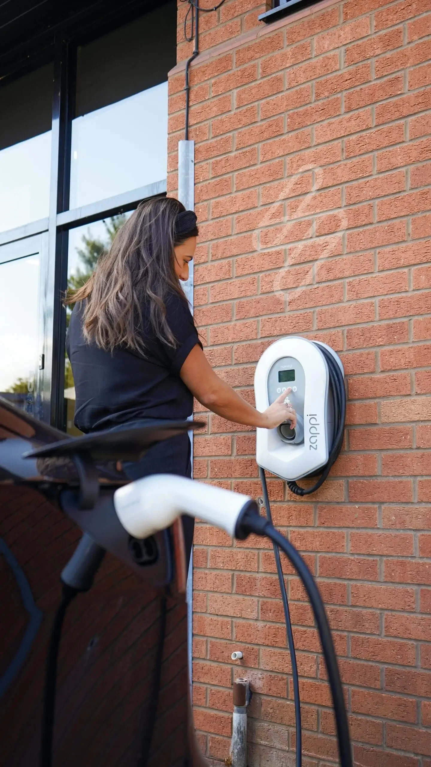 A lady charging her electric car from an EV charger at home