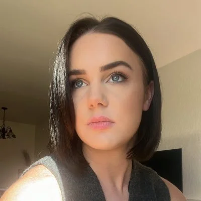 Close-up of a woman with short dark hair and blue eyes looking to the side.