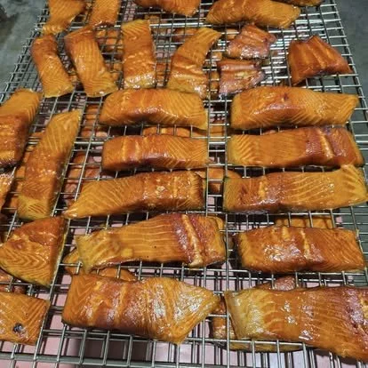 Several pieces of cooked salmon fillets on a wire cooling rack.