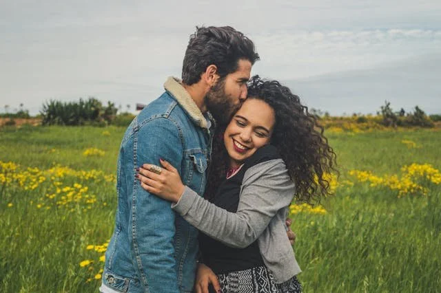 A couples kissing in a field