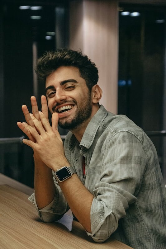a smiling guy with an apple watch on and a plaid shirt