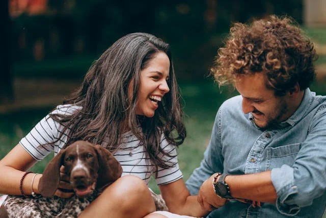 a couple with a puppy laughing outside