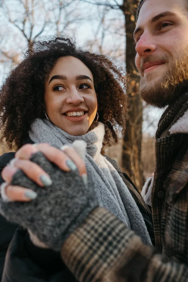 a couple outside in winter smiling and holding hands