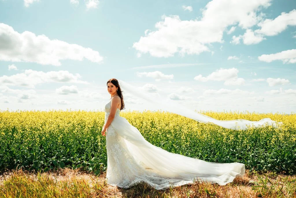 Gorgeous bridal photography of bride in front of blooming canola fields in the Alberta prairies at the best secret wedding venue near Drumheller, Open Country Farm