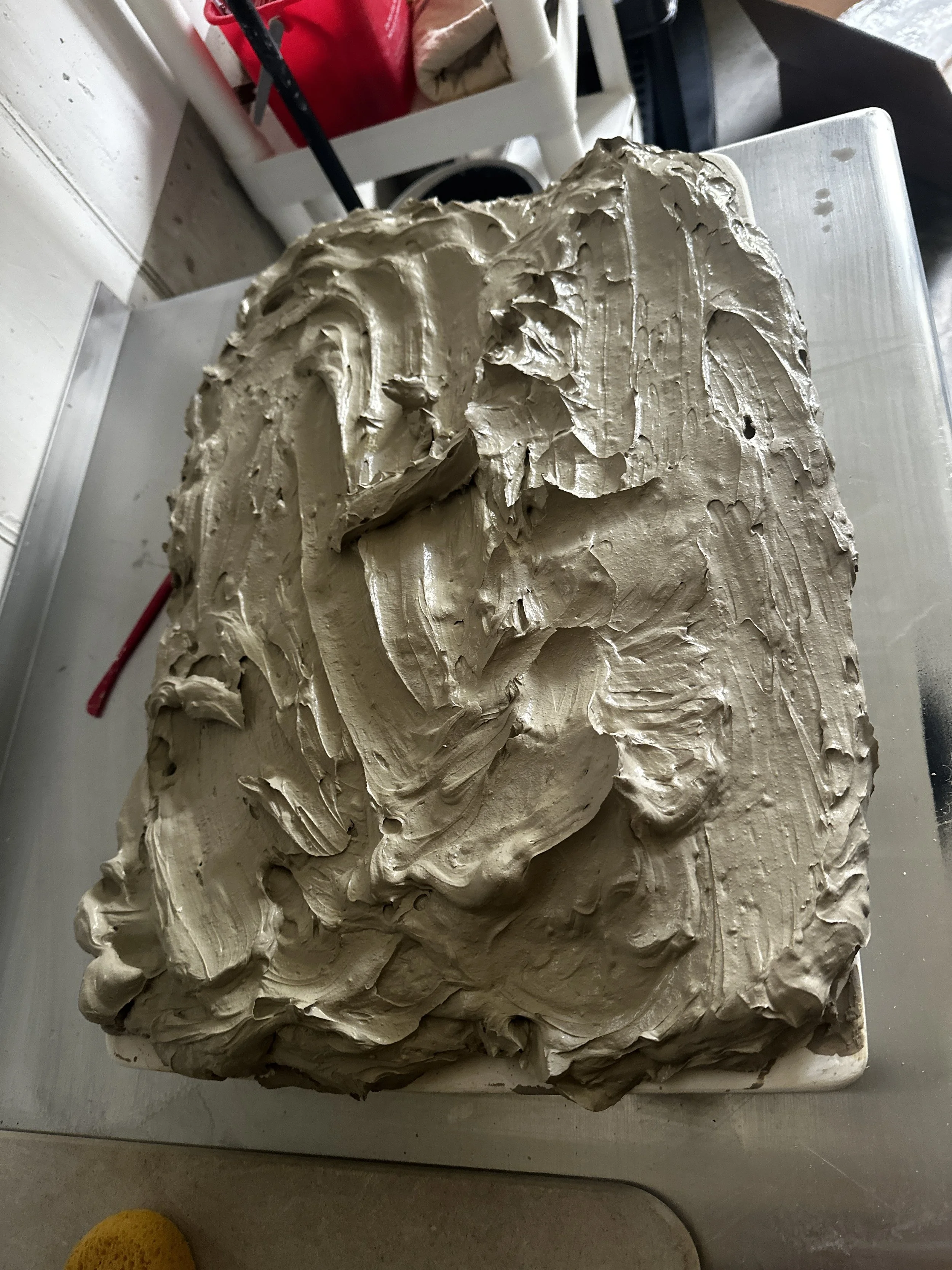 A rectangular block of beige or light brown frosting or icing with textured, swirling patterns, placed on a flat surface.