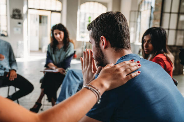 People participating in a support or therapy group discussion in a well-lit room.