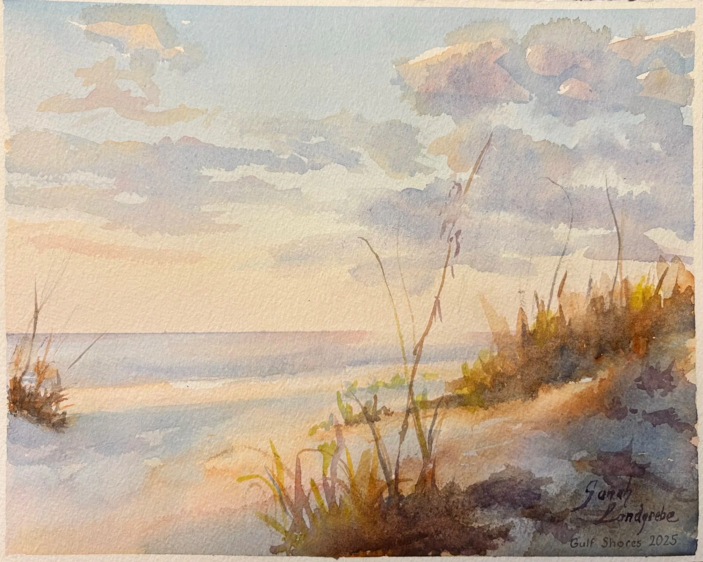 Watercolor painting of a Gulf Shores beach scene during sunset, featuring a sandy shore with grass and shrubs, calm waves, and a pastel-colored sky with scattered clouds.