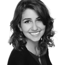 Black and white portrait of a woman with curly hair smiling at the camera.