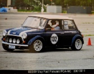 A classic Mini Cooper car participating in a race or driving event, marked with the number 132, on an outdoor course with traffic cones.