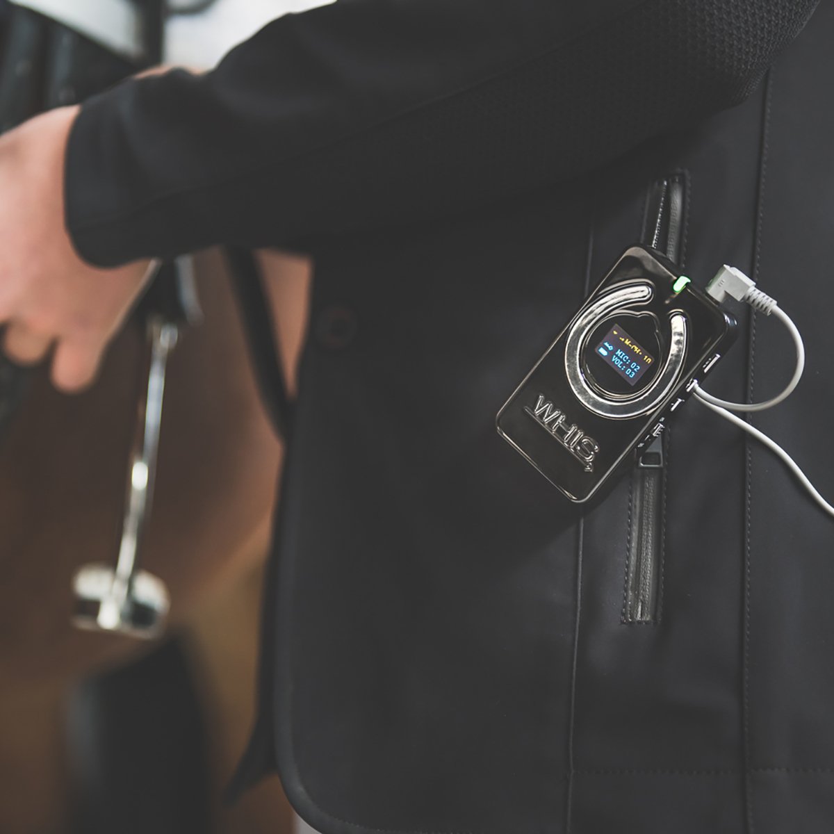 Close-up of a person's pocket with a digital portable music player attached to their clothing, plugged into headphones.