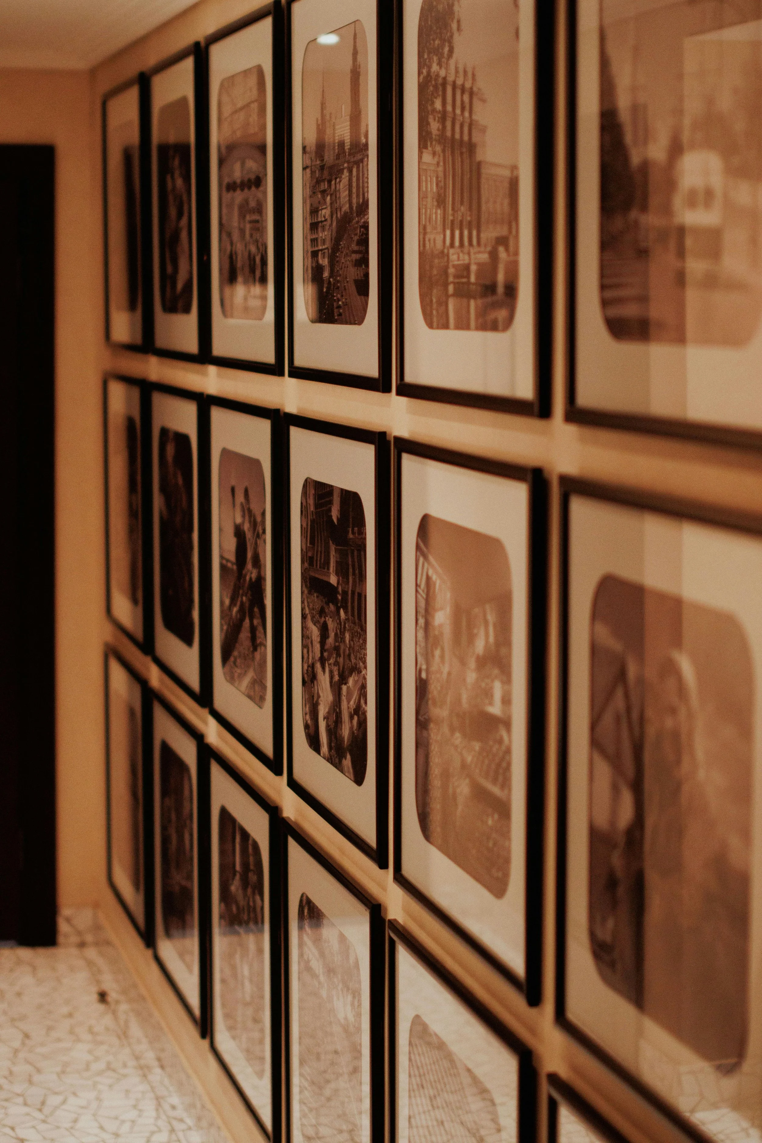 A wall decorated with multiple rows of framed sepia-toned photographs of cityscapes and street scenes.