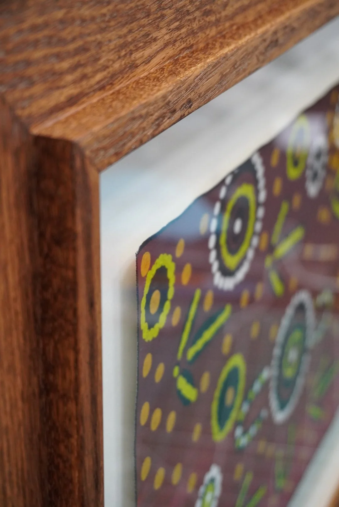 Close-up of a wooden frame around a colorful abstract painting with circular and dotted patterns.