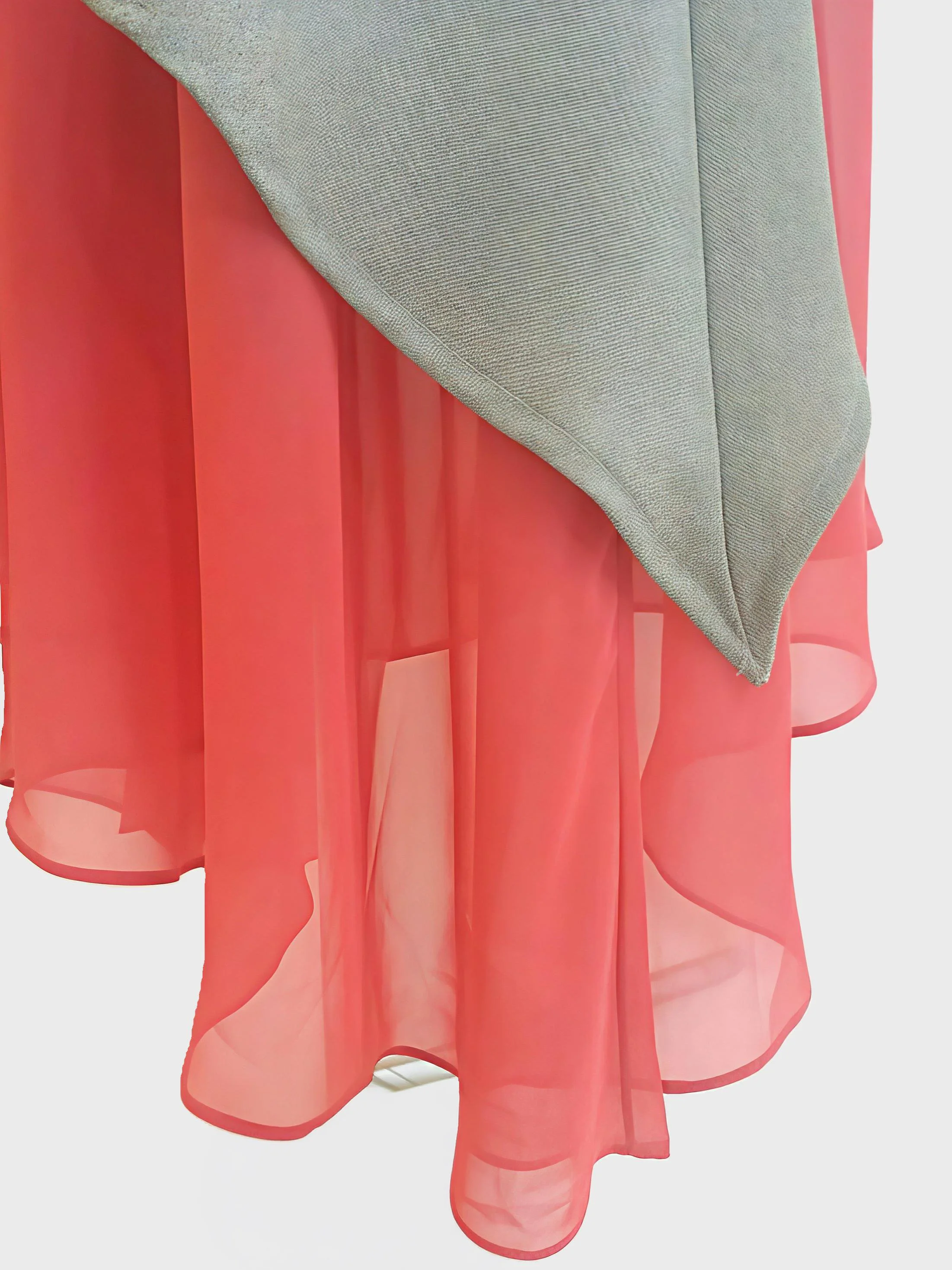 Close-up of a skirt hem, a layered pink sheer chiffon fabric underneath a light beige fabric.