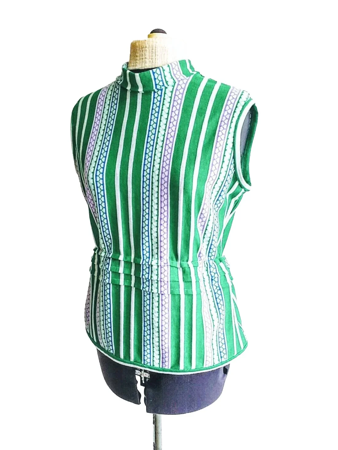 A retro inspired sleeveless, high-collared blouse with green, white, and purple vertical stripes and intricate patterns, displayed on a dress form against a white background.