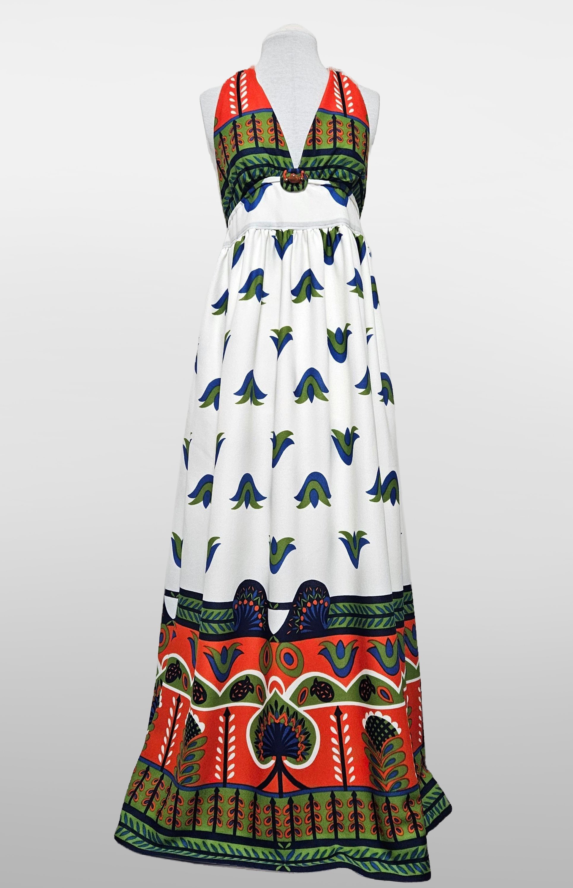 A retro colorful, sleeveless, maxi dress with a vibrant, patterned design including floral and abstract motifs in green, blue, red, black, and white, displayed on a mannequin. One of a kind design.