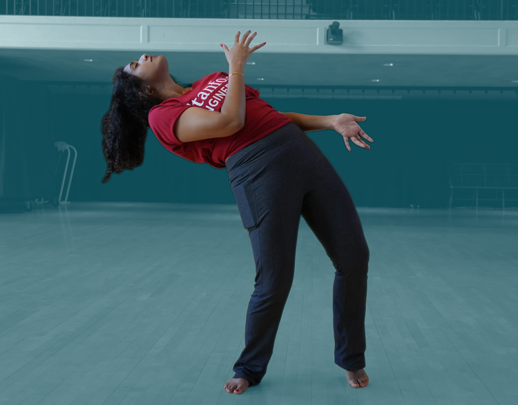 A woman in a red shirt and dark pants dancing at a gym.