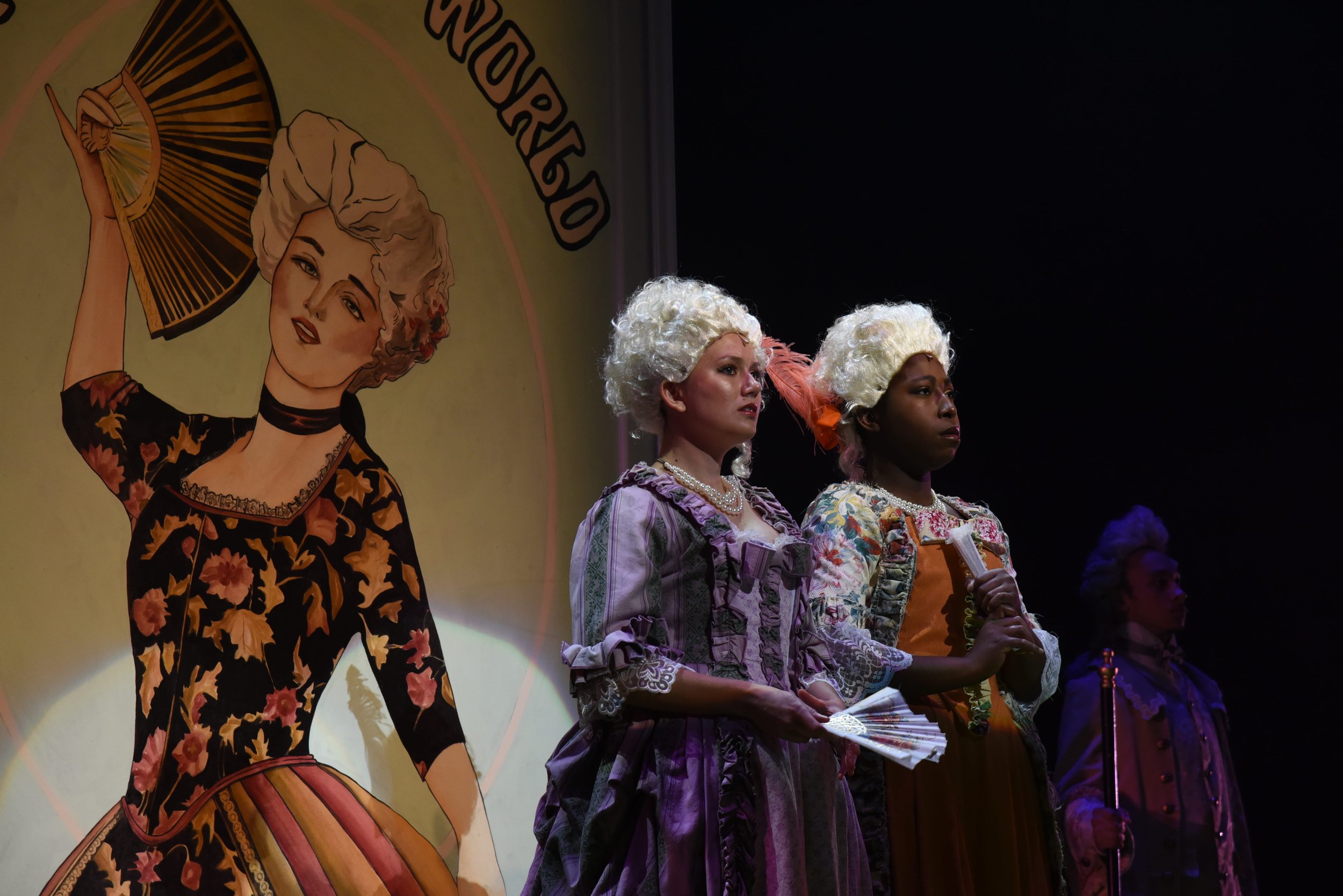 People dressed in period costumes standing on stage in front of a backdrop featuring an illustration of a woman in a vintage outfit holding a fan.