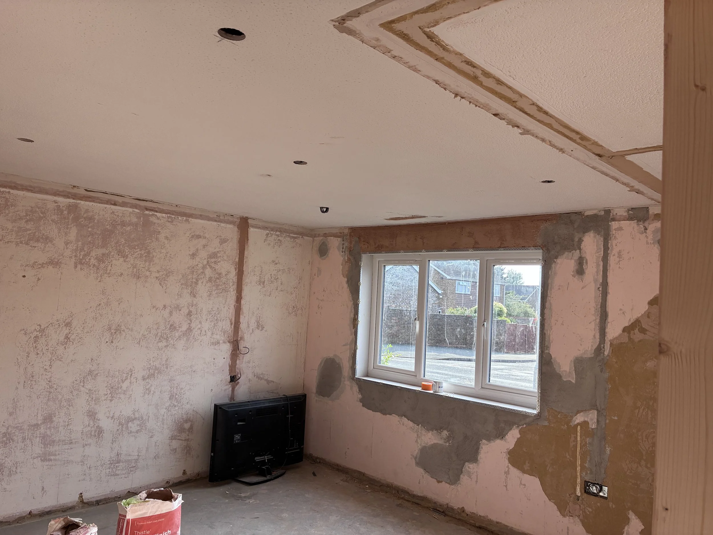 Room prepared for over skimming during a four-bedroom bungalow renovation in St Neots, with existing walls ready for fresh plaster.