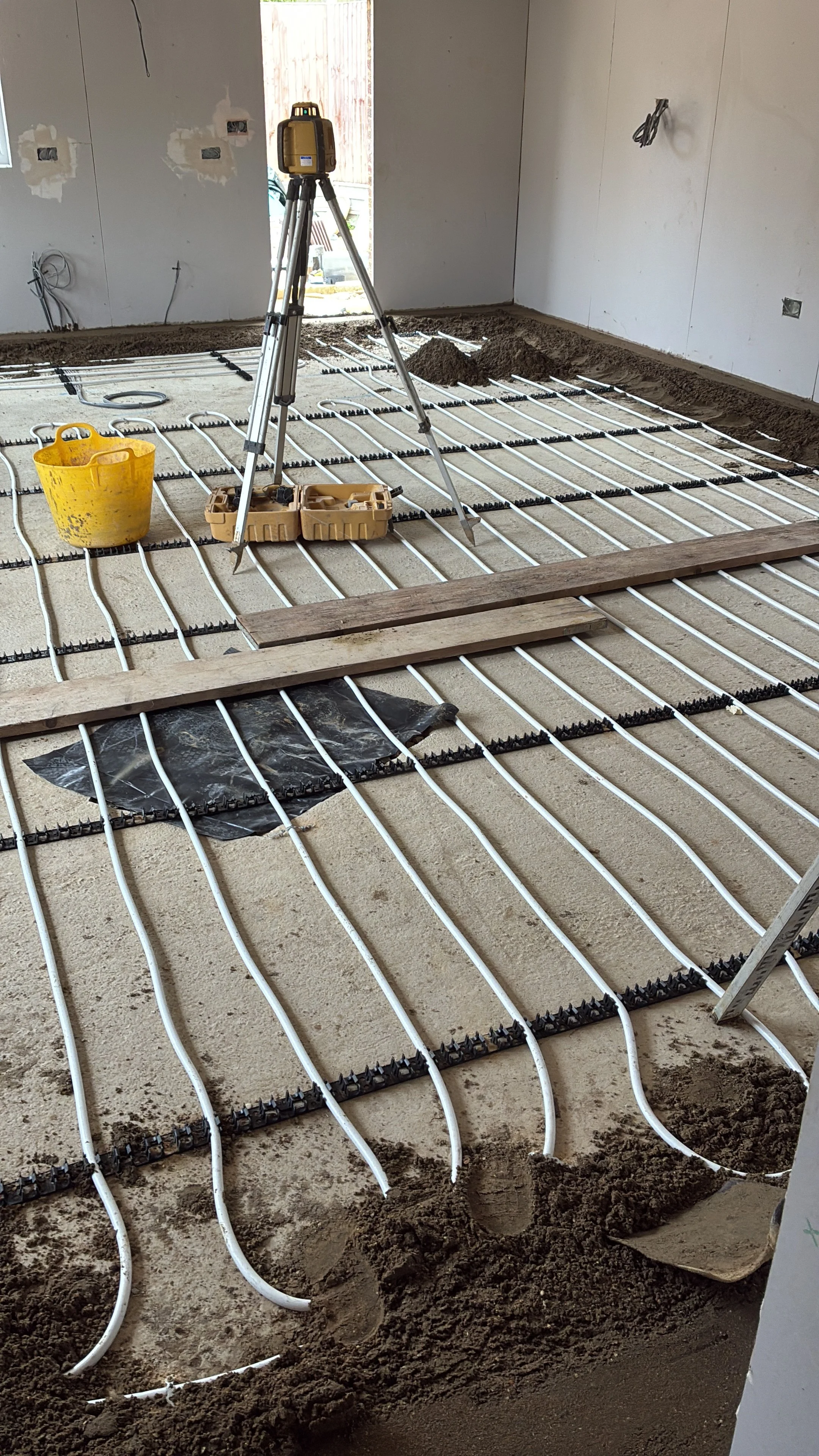 Traditional sand and cement floor screed being laid over underfloor heating during a bungalow renovation in St Neots.