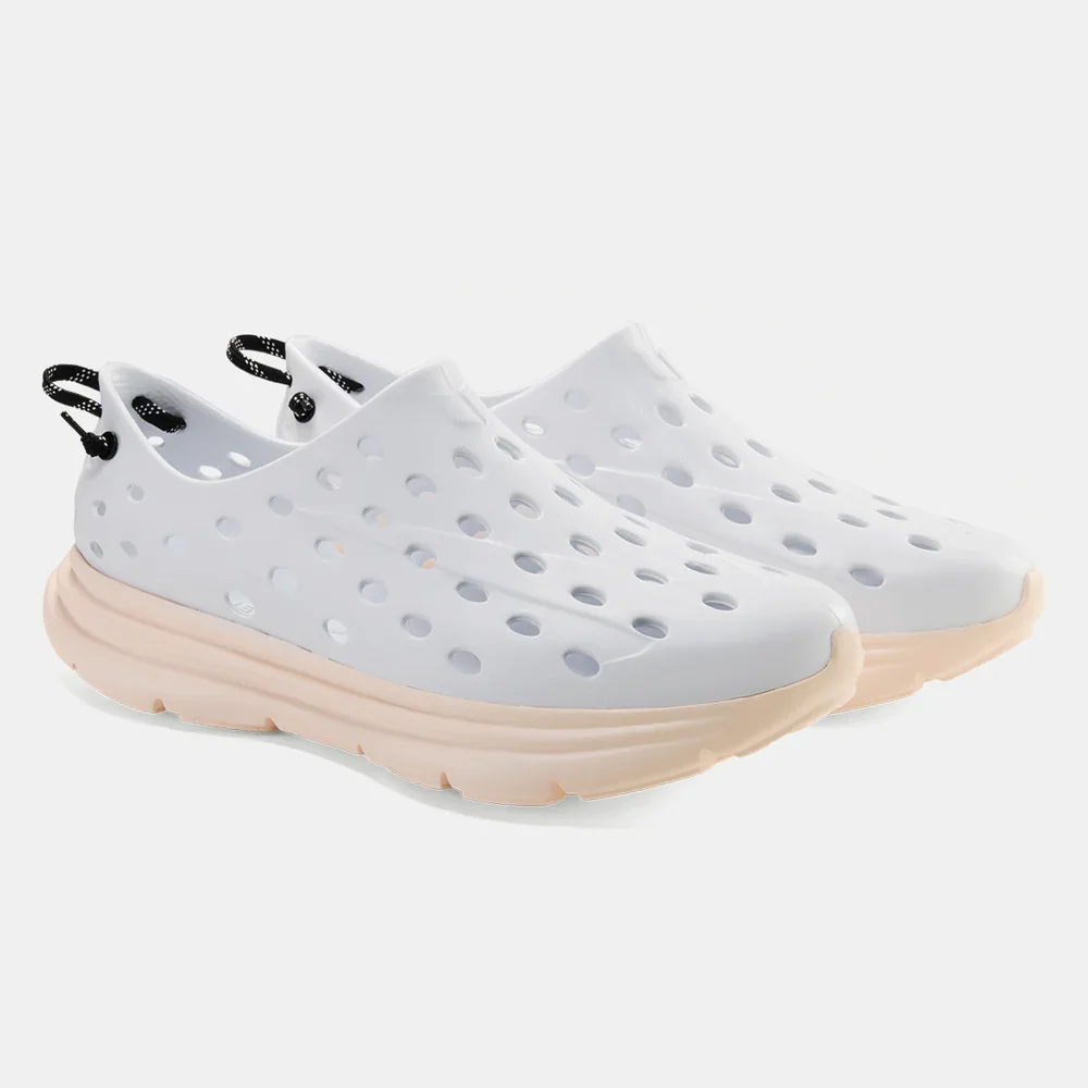 Pair of white slip-on shoes with circular cutouts and beige soles, against a plain white background. Kane.
