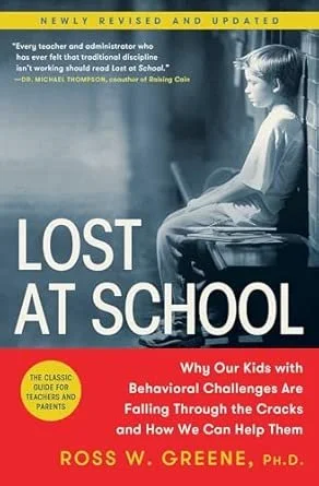 Cover of the book titled 'Lost at School' by Ross W. Greene, Ph.D., features a black-and-white photo of a young girl sitting alone on a school desk with her head slightly bowed, set against a predominantly blue background with yellow and red accents.