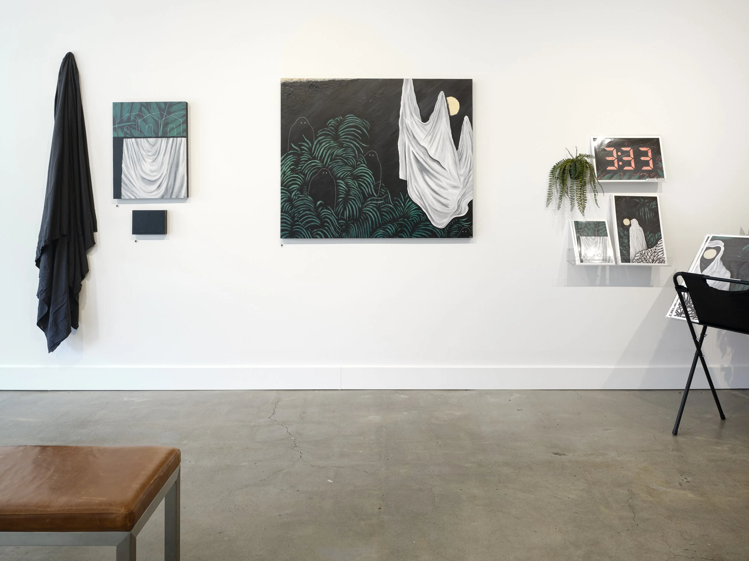 Gallery wall with paintings, digital clock, shelf with framed art, potted plant, black chair, and brown leather bench in a modern art space.
