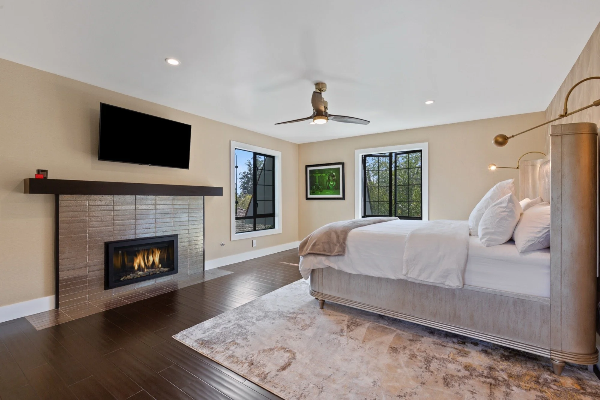 Modern bedroom with a bed, window, fireplace, and TV on the wall.