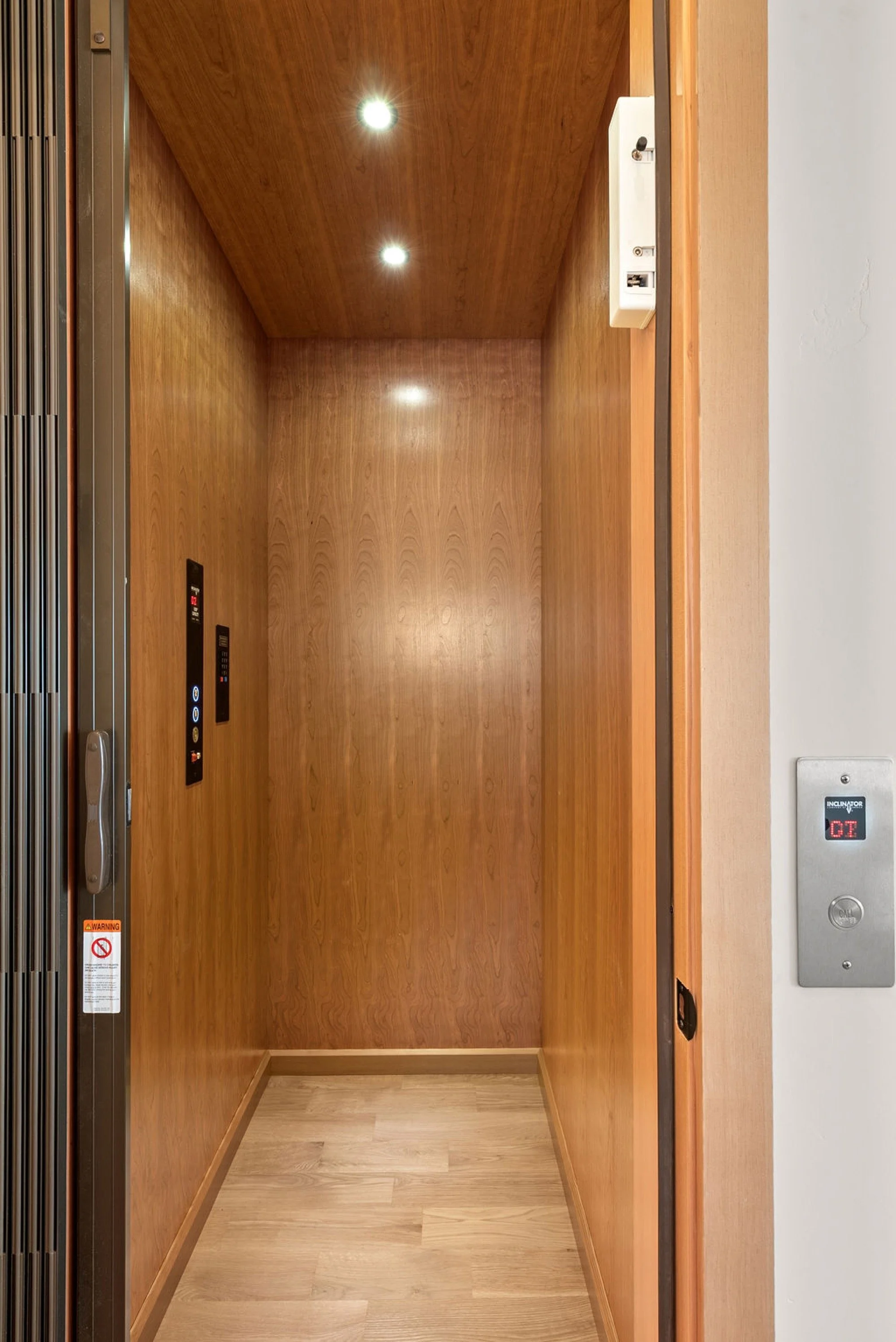 Empty hallway with wood interior, illuminated ceiling lights, and a door.