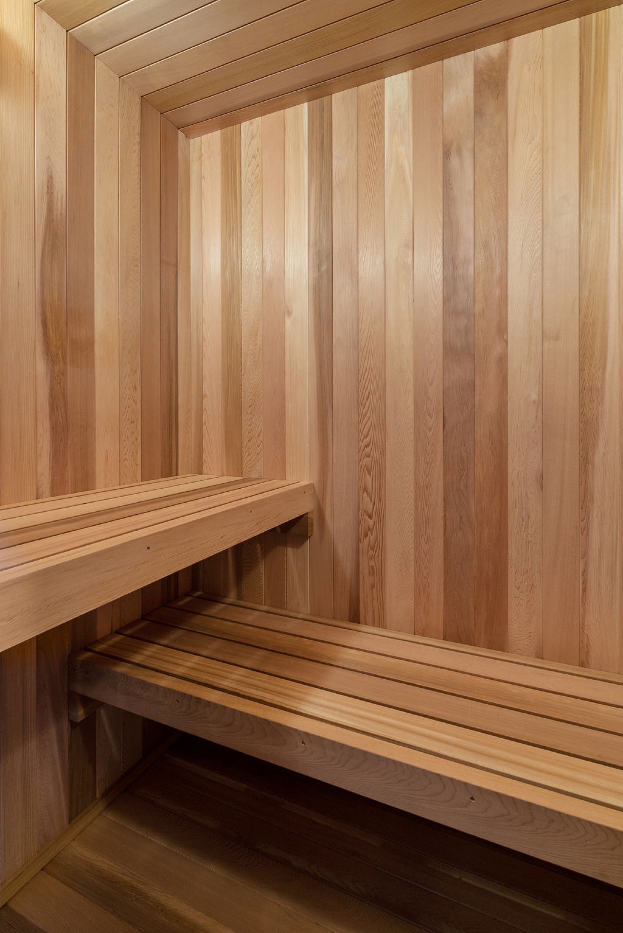 Interior of a wooden sauna with vertical wooden panel walls and two wooden benches.