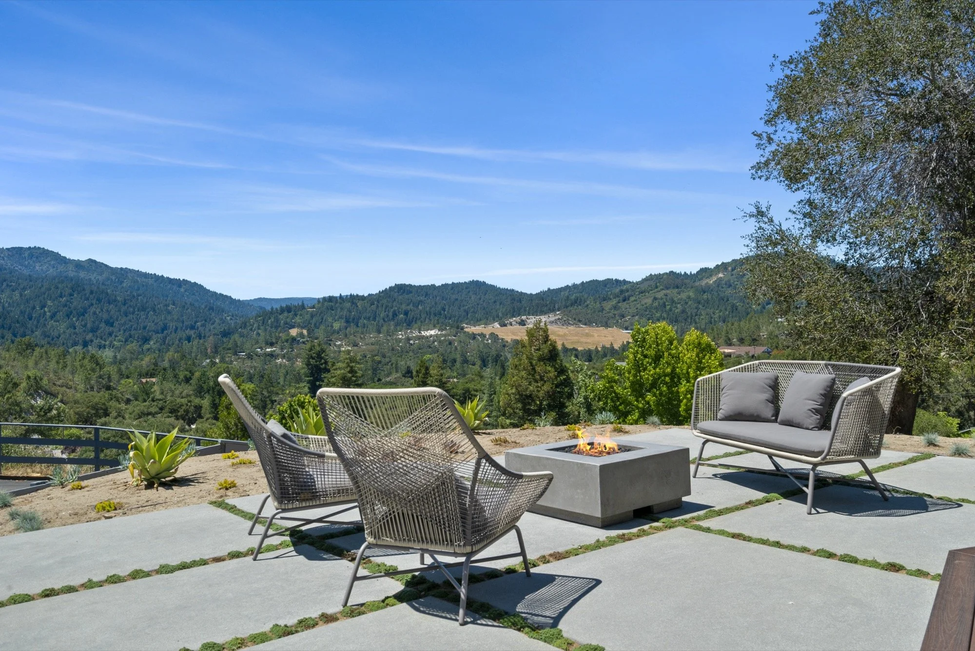 Outdoor patio with modern chairs, a fire pit, and a scenic mountain view under a clear blue sky.