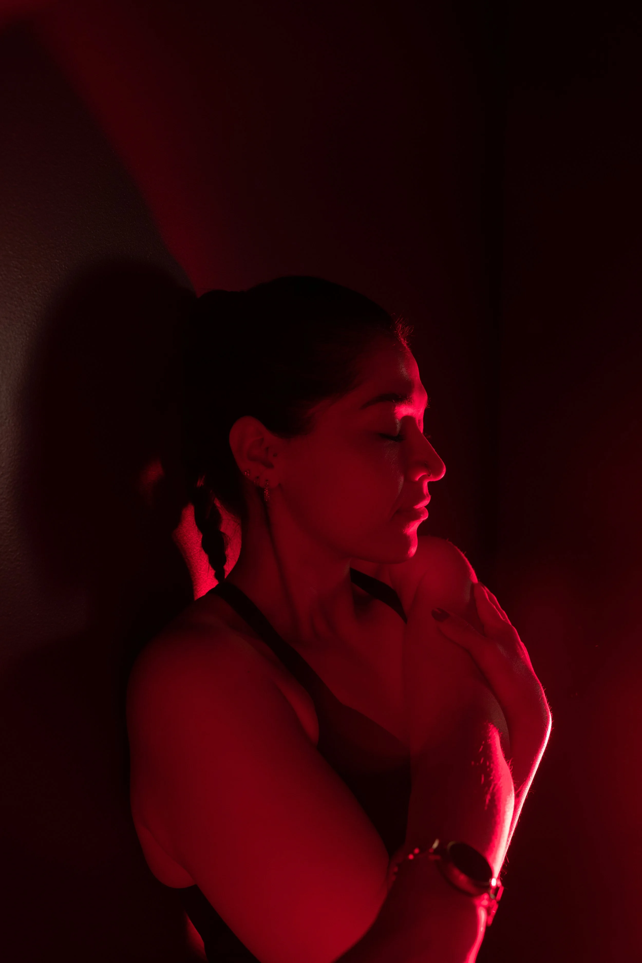 Silhouette of a woman kneeling with hands on her knees, in a dark room with red lighting.
