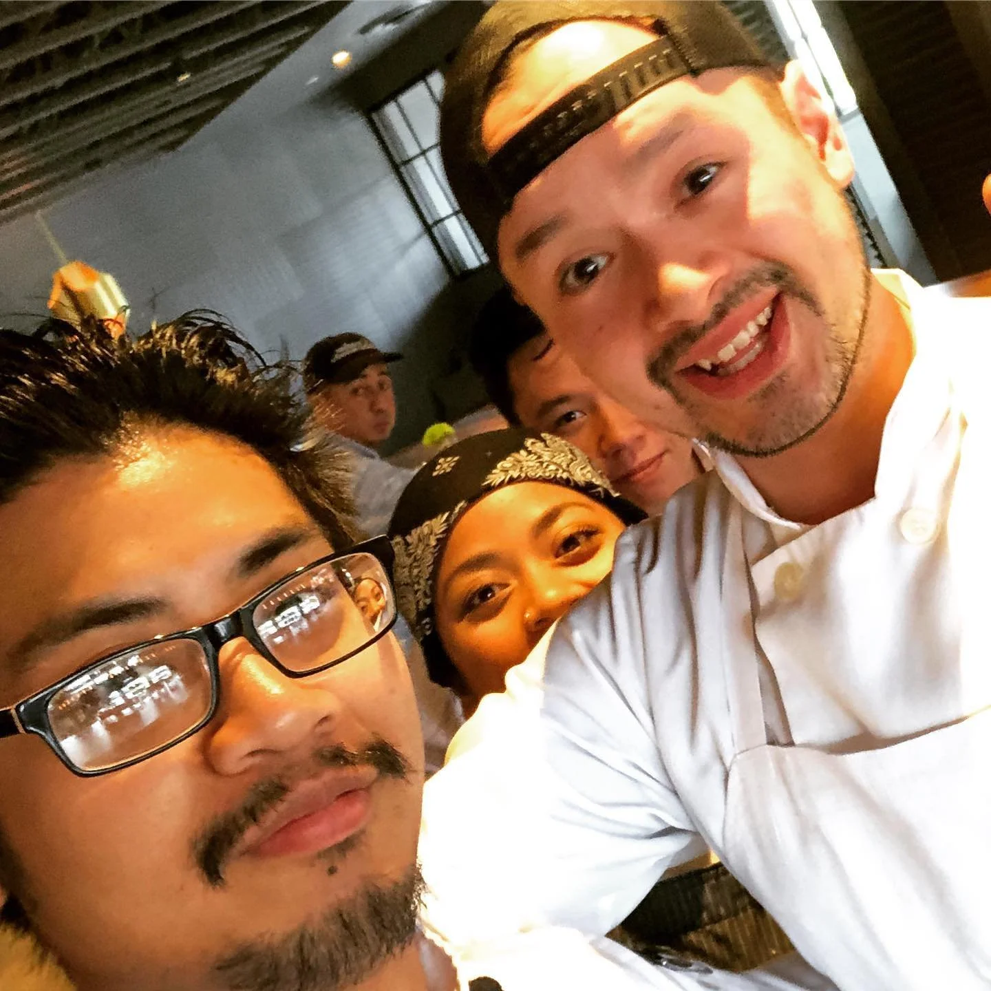 A group of diverse friends taking a selfie at a restaurant, smiling and enjoying their time together.