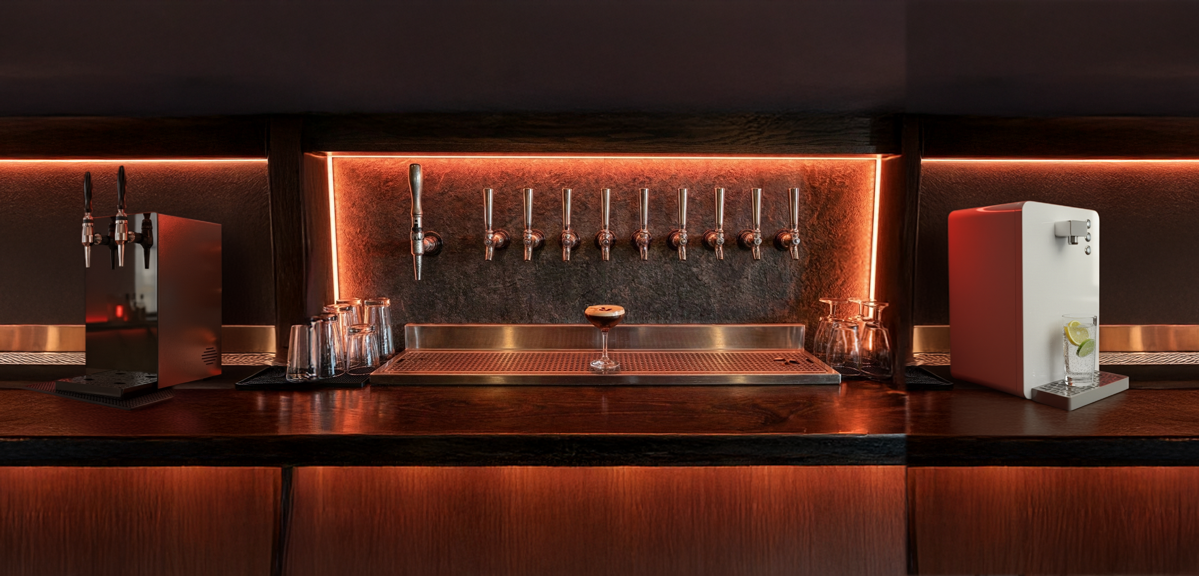Bar counter with beer taps, glasses, and a drink dispenser with lemon and lime slices in a dimly lit setting.