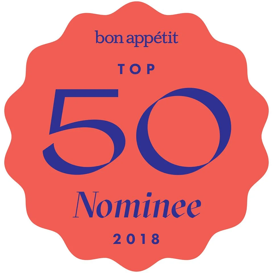 A red badge with scalloped edges featuring blue text that says "bon appétit TOP 50 Nominee 2018."