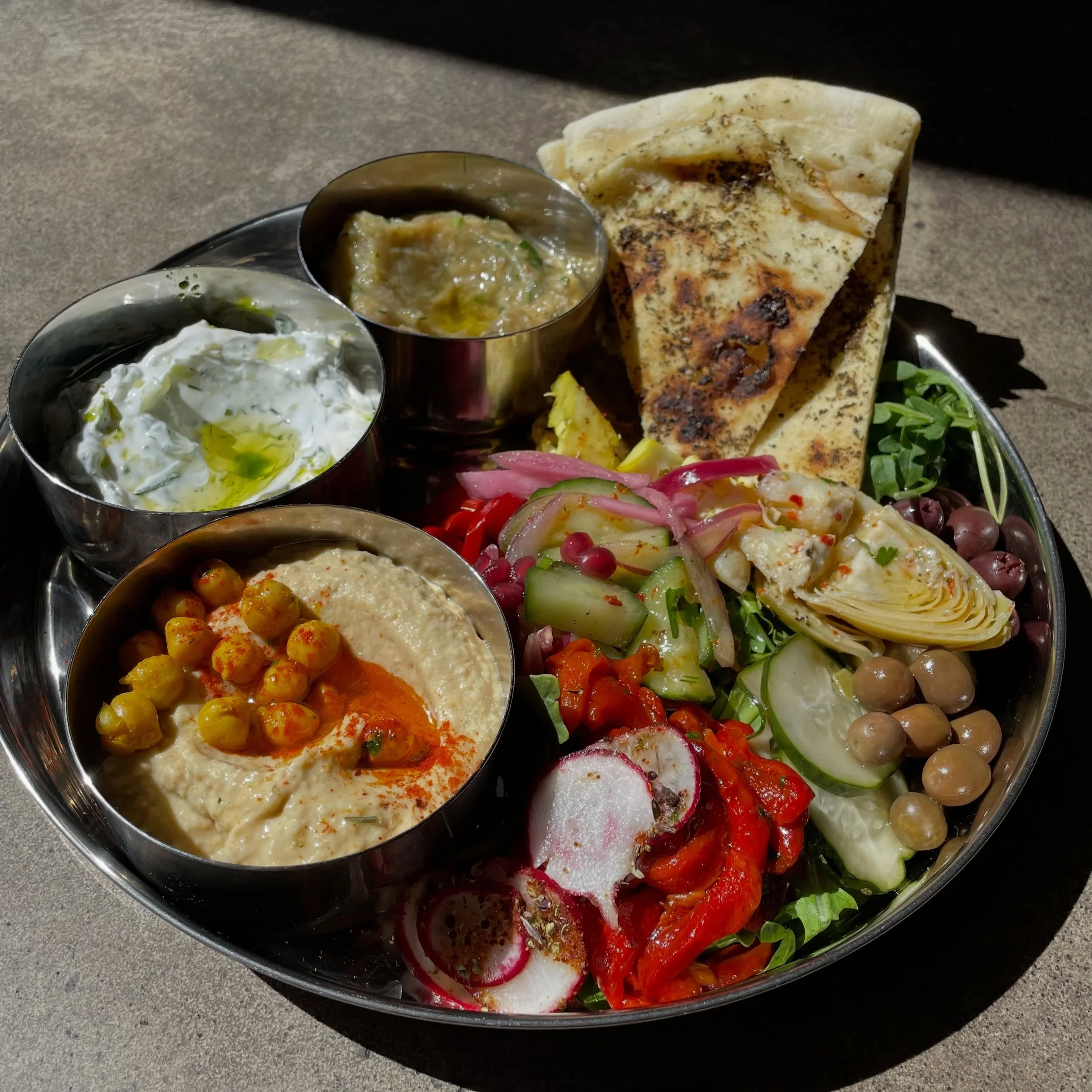 A spread made for the table.

House-made hummus, cool tzatziki, melitzanosalata, warm pita, olives, and pickled vegetables&mdash;a little bit of everything, meant for sharing.

Open Tuesday&ndash;Saturday, 12pm&ndash;10pm.
&bull;
#stina #mezze #medit